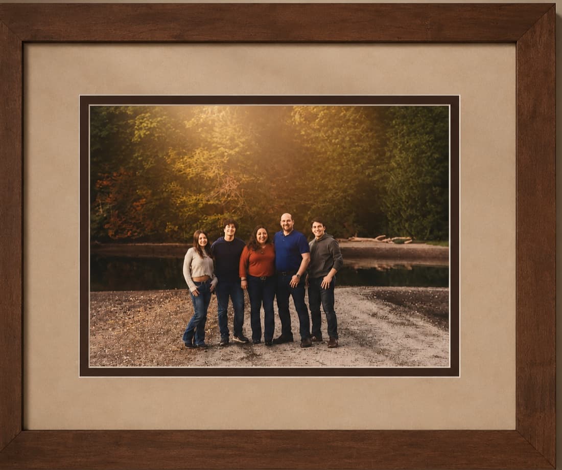 Family portrait framed in a warm walnut frame with a wide linen mat and dark accent bevel by Redhawk Framing Studio in Vancouver, WA