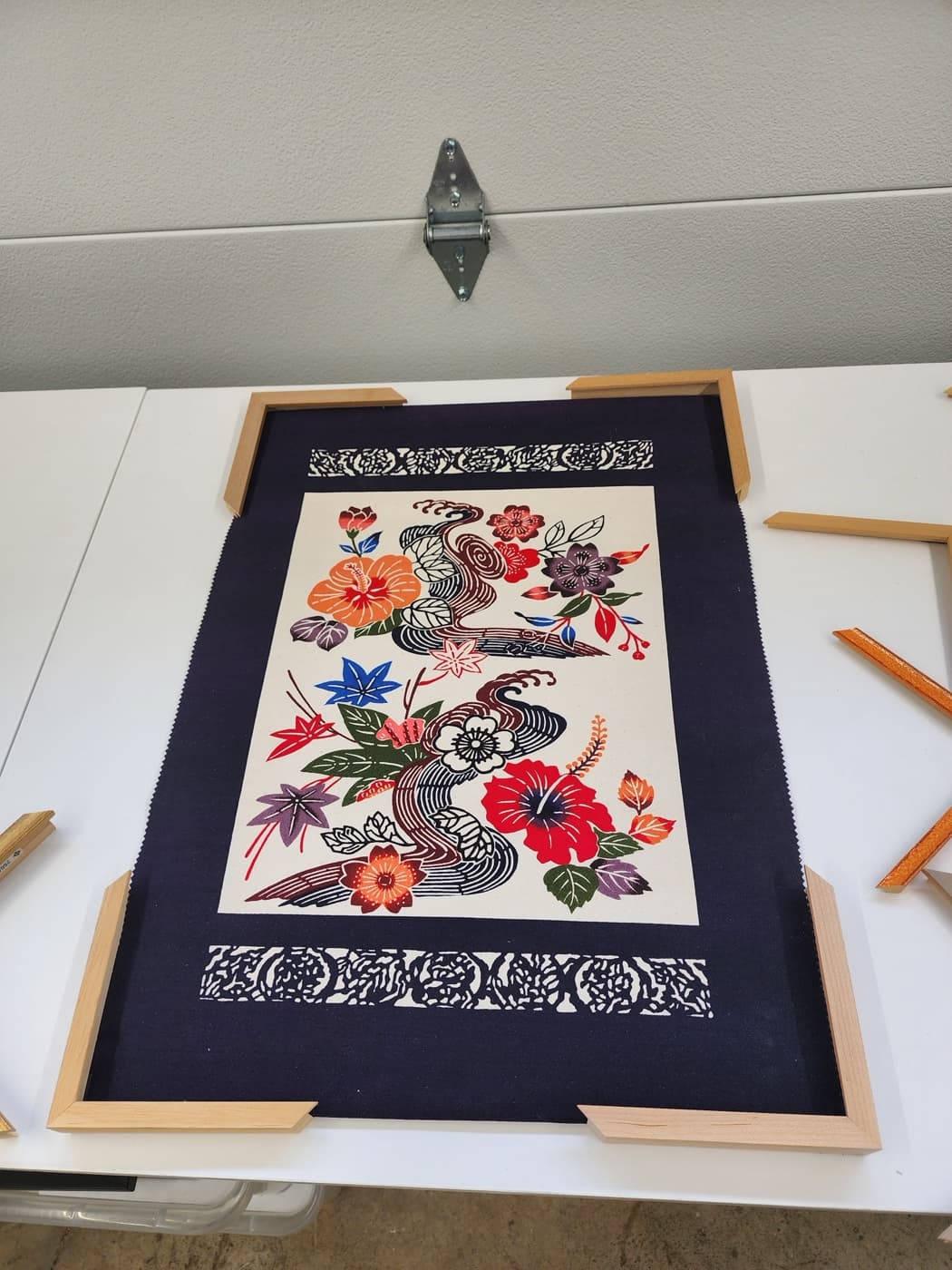 Framed floral needlework with a navy mat, conservation framed by Redhawk Framing Studio in Vancouver, WA