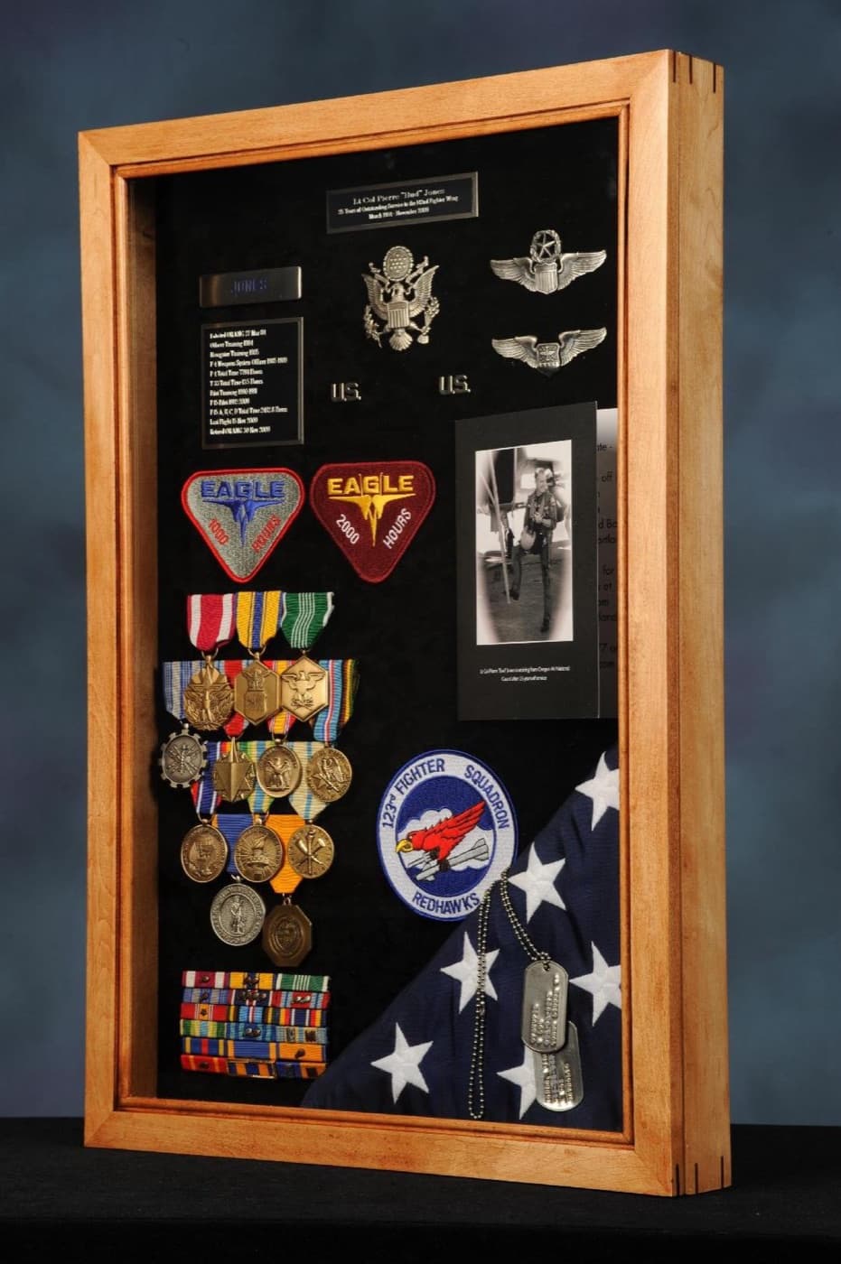 Military shadow box with service medals, ribbons, unit patches, and a folded flag framed by Redhawk Framing Studio in Vancouver, WA